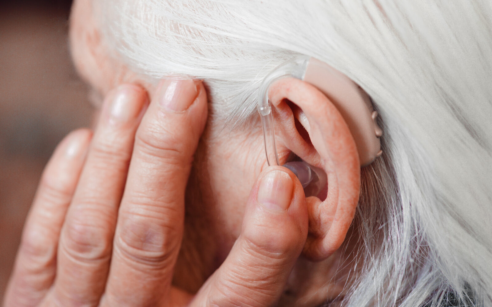 Closeup senior woman with hearing aid in her ear Health care, hear amplify, device for the deaf