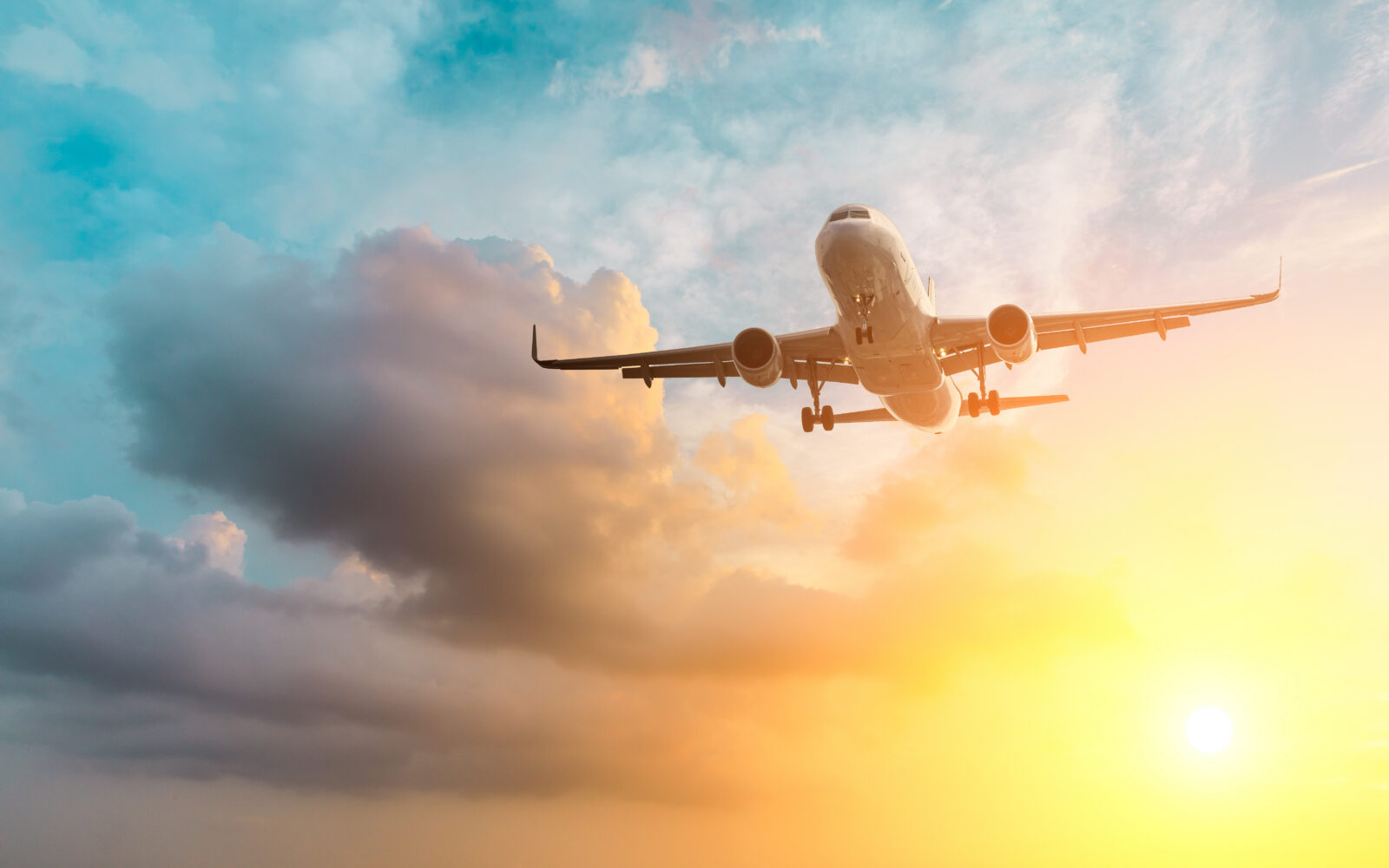 Commercial airplane flying above dramatic clouds during sunset
