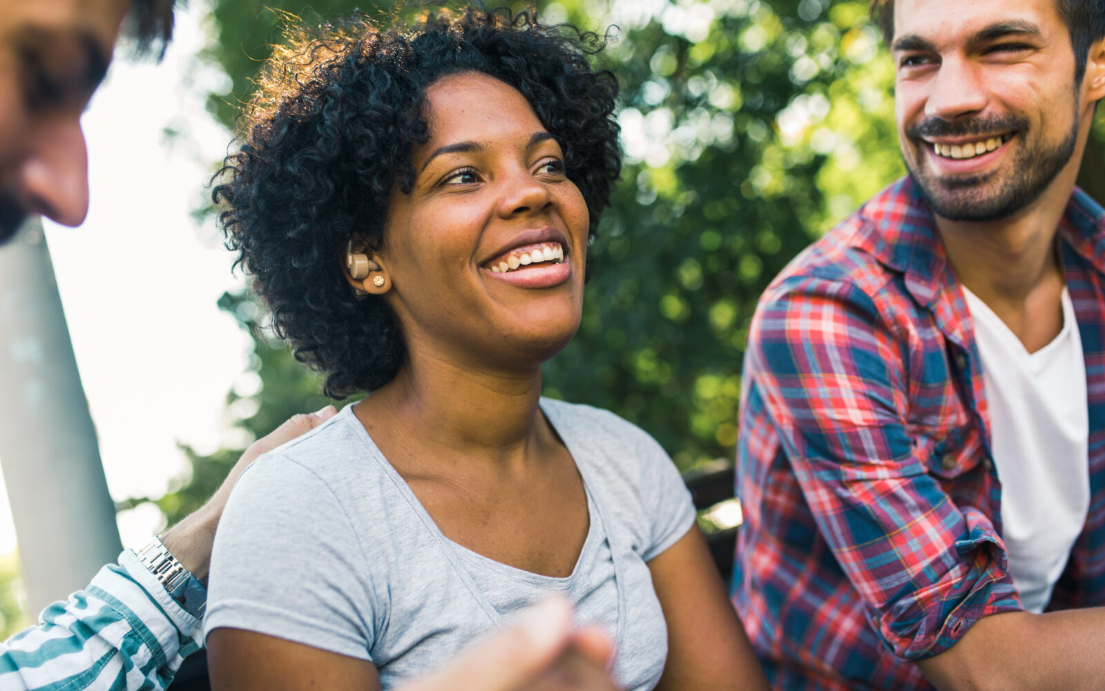 Woman with ear hearing problem having fun with her friends in the park