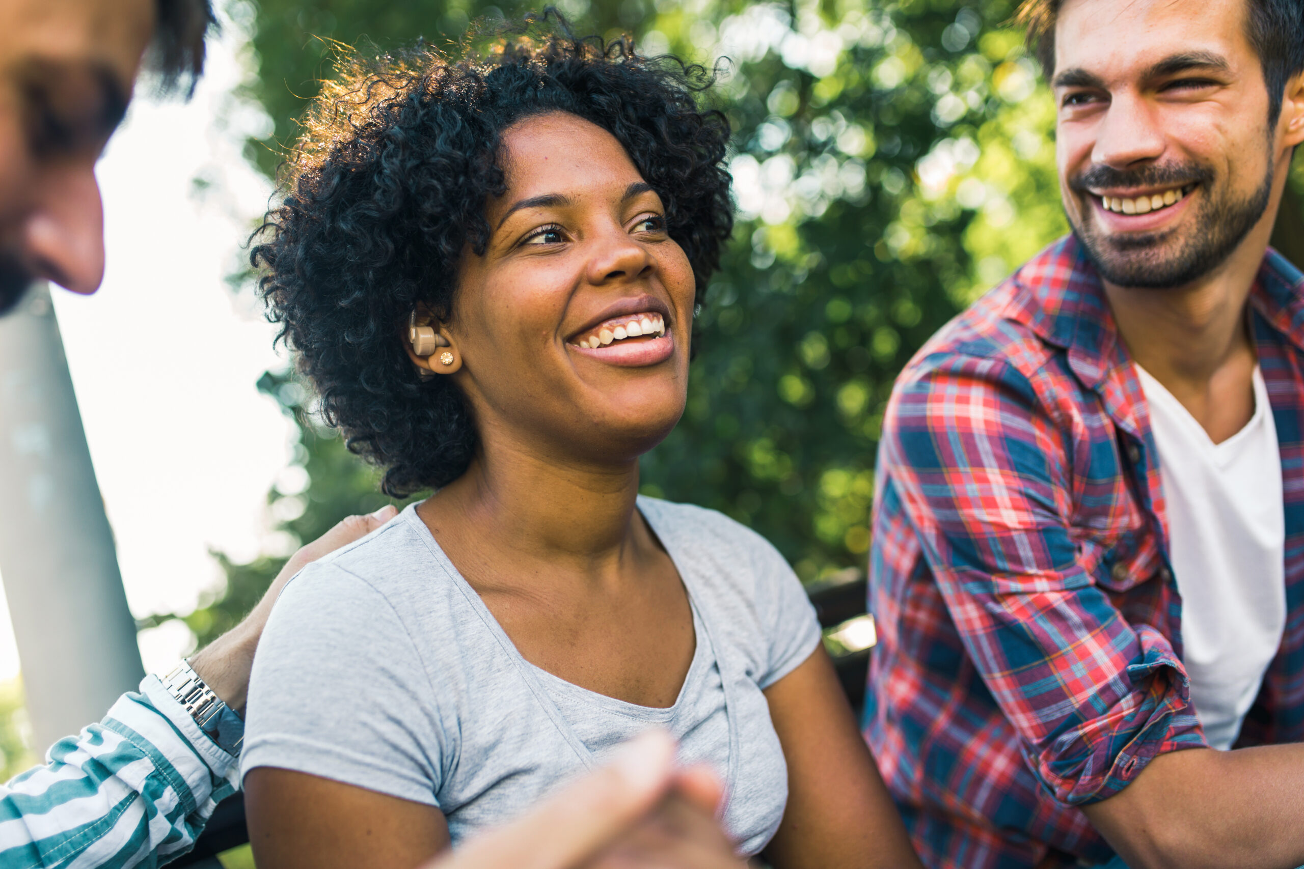 Woman with ear hearing problem having fun with her friends in the park