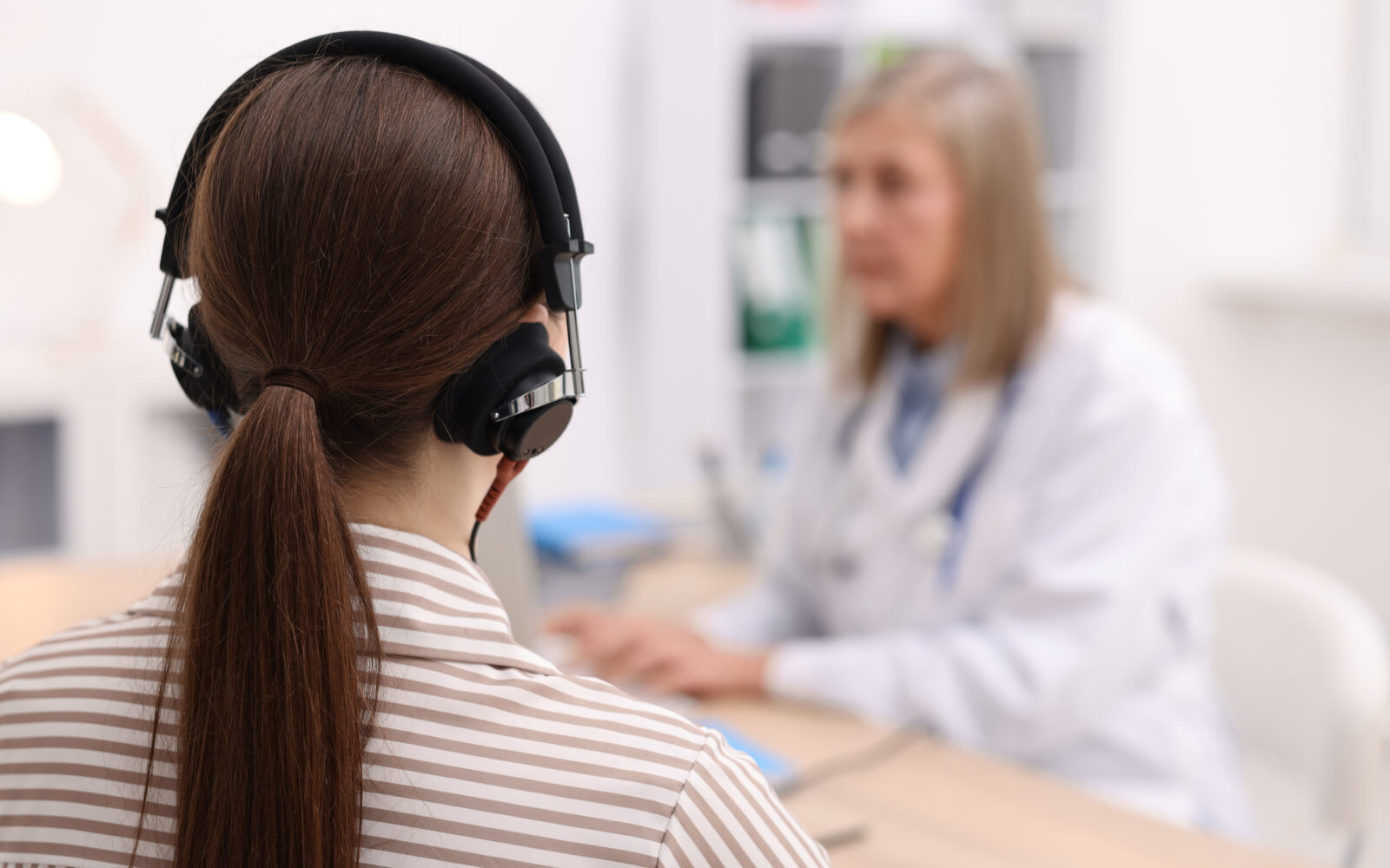 Patient with audiometric headphones undergoing hearing test in clinic, selective focus Space for text