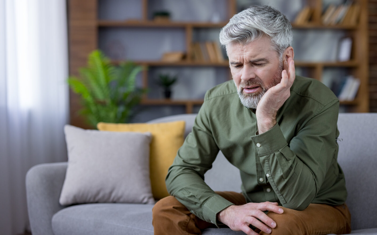 Mature man suffering from severe earache and pain at home