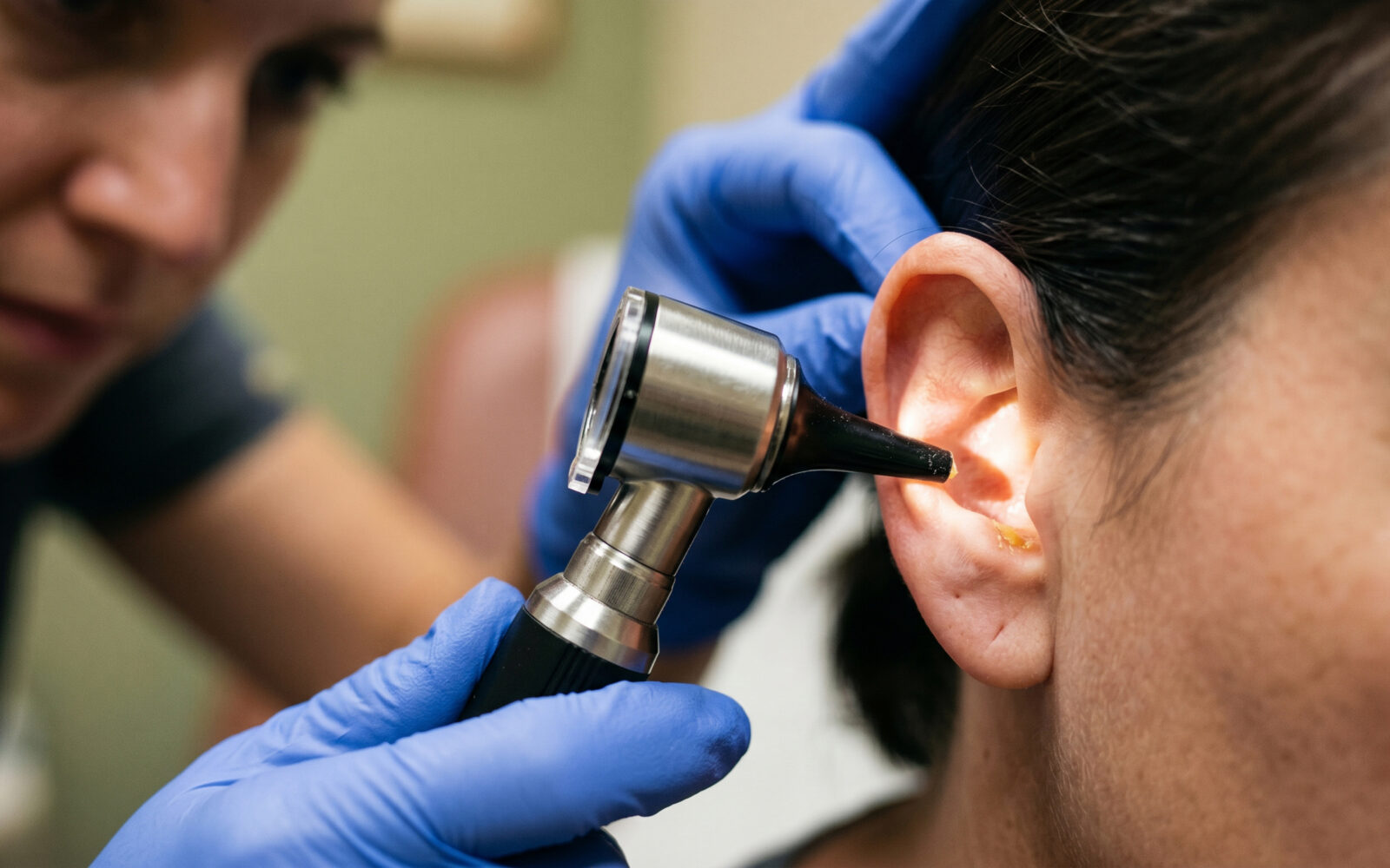 Close up of a clinician examining an ear canal with an otoscope, medical diagnostic check for infection, inflammation or earwax buildup, healthcare and ENT examination concept