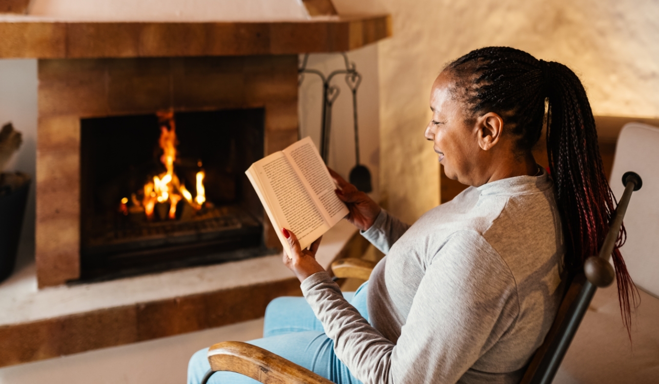 senior woman reading in front of fireplace