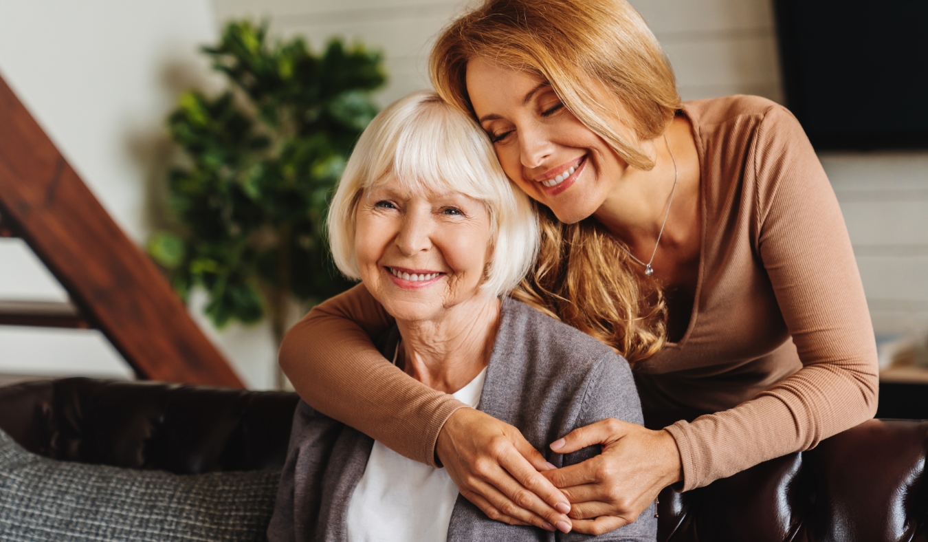 adult daughter hugging senior mother