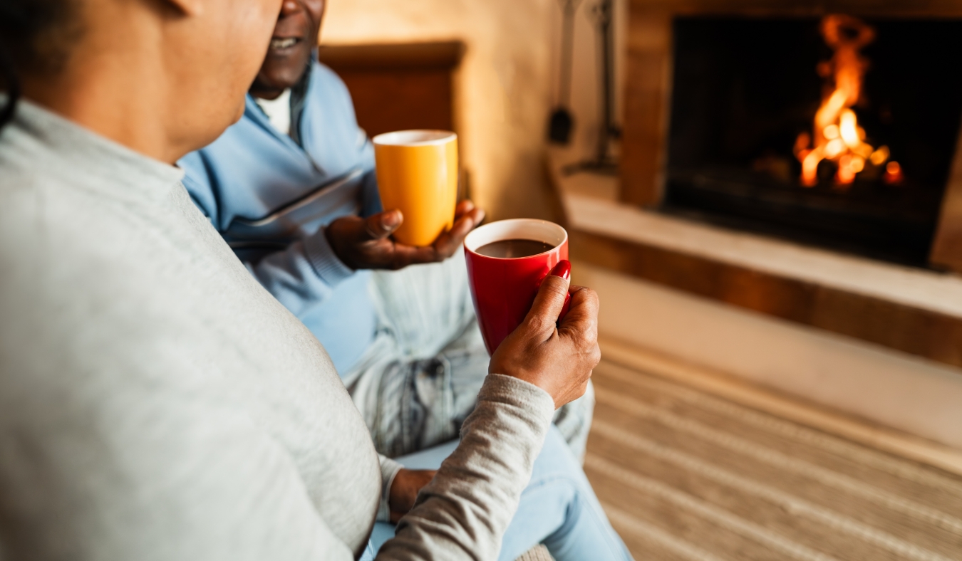 couple drinking coffee by fireplace
