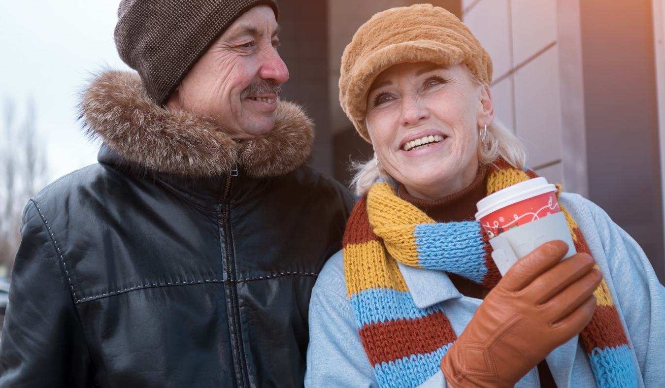 couple walking along city street with coffee