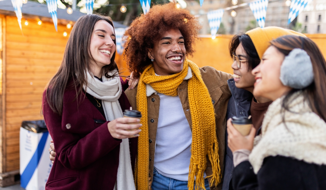 group of diverse friends drinking hot drinks in a christmas marke