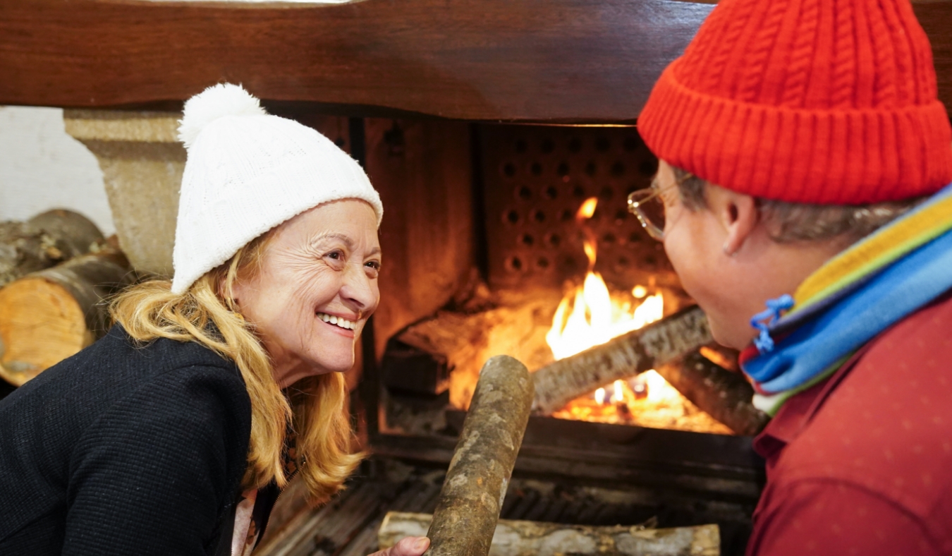 older couple adding wood to fireplace