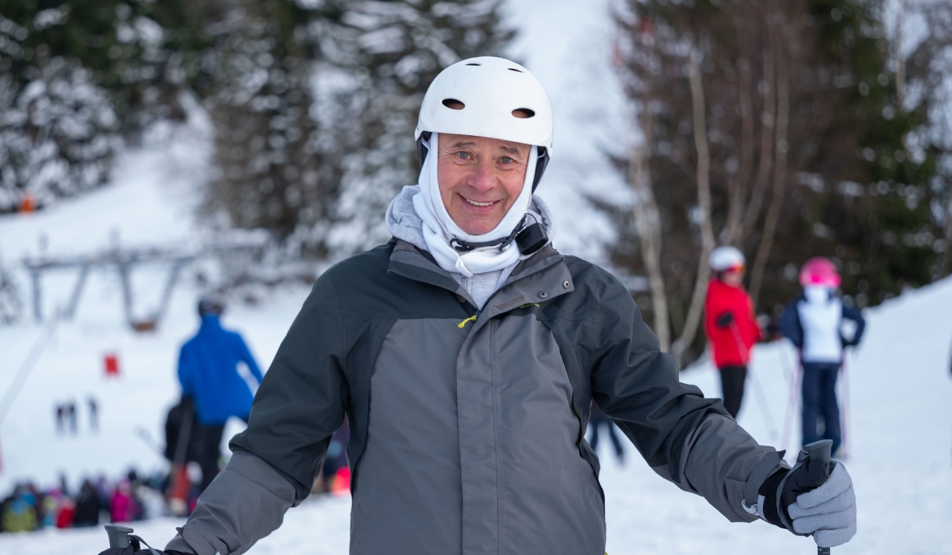 older man smiling while skiing