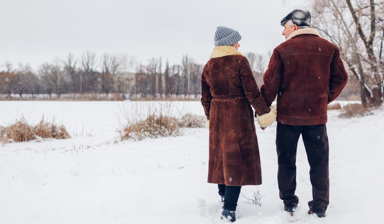 senior couple holding hands walking by frozen lake