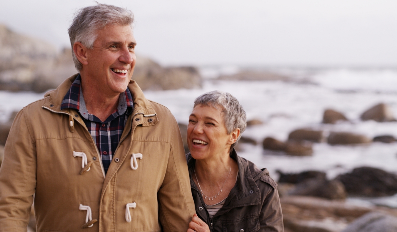 senior couple walking along chilly beach
