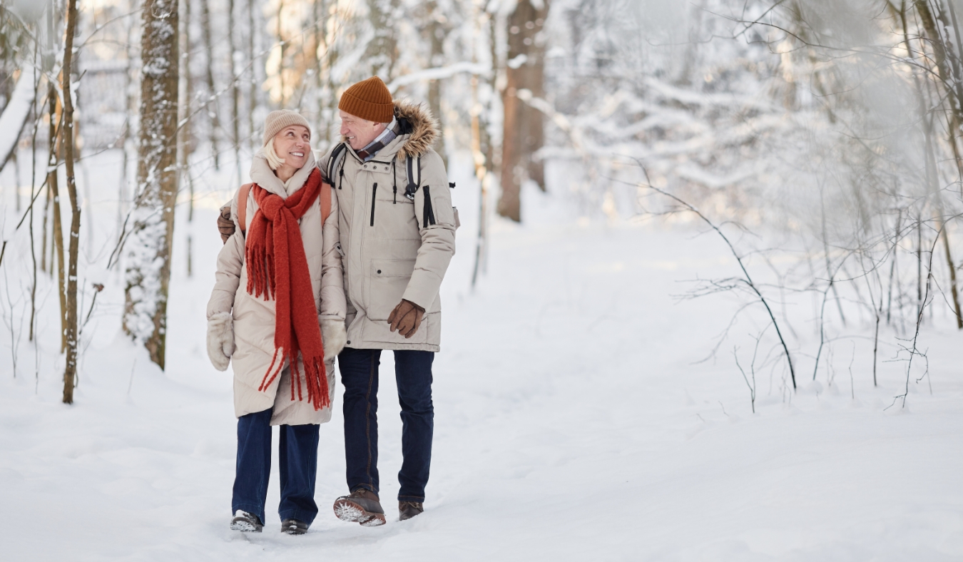 senior couple walking through snowy landscape