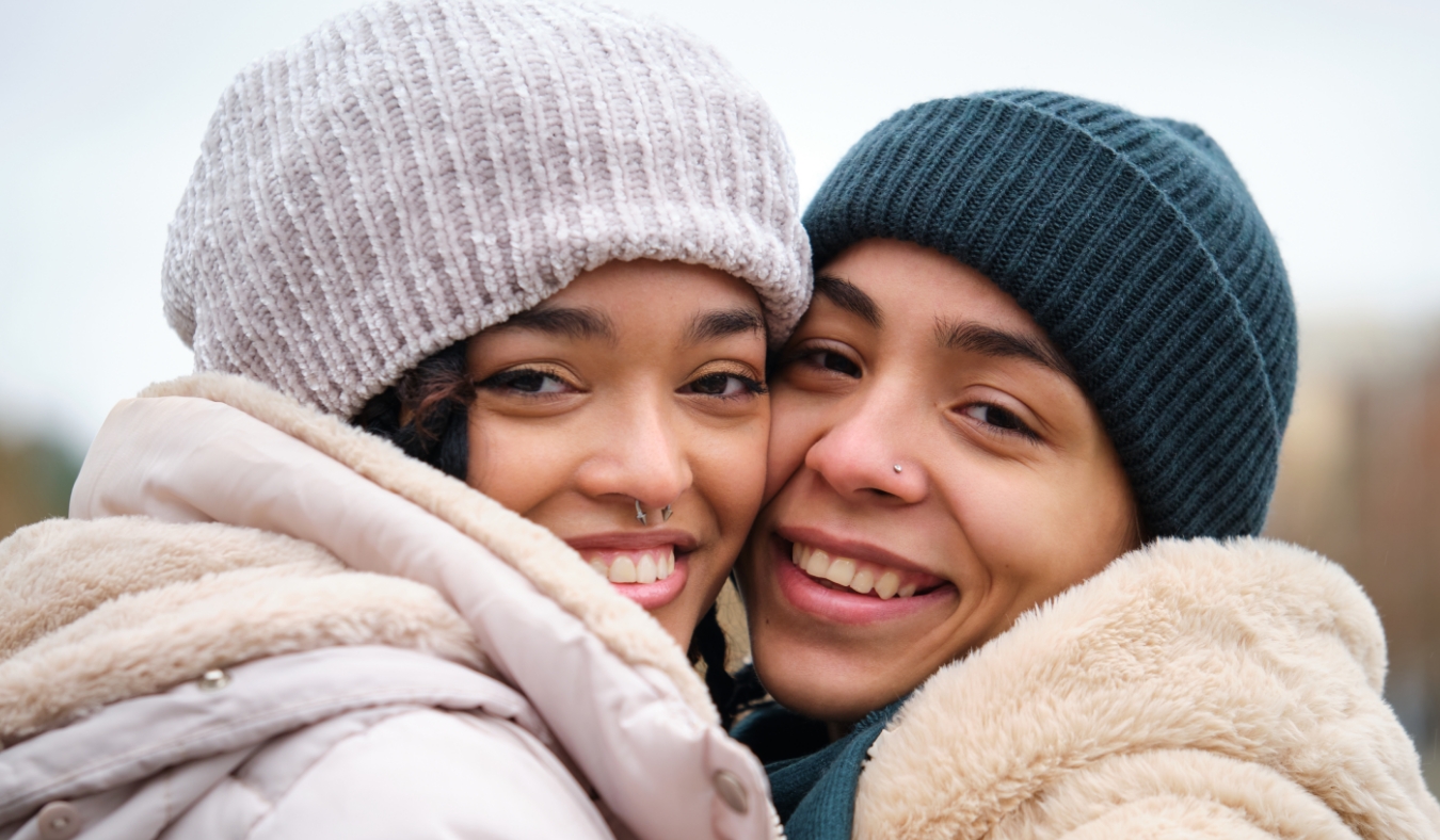 two woman smiling hugging on a winter day