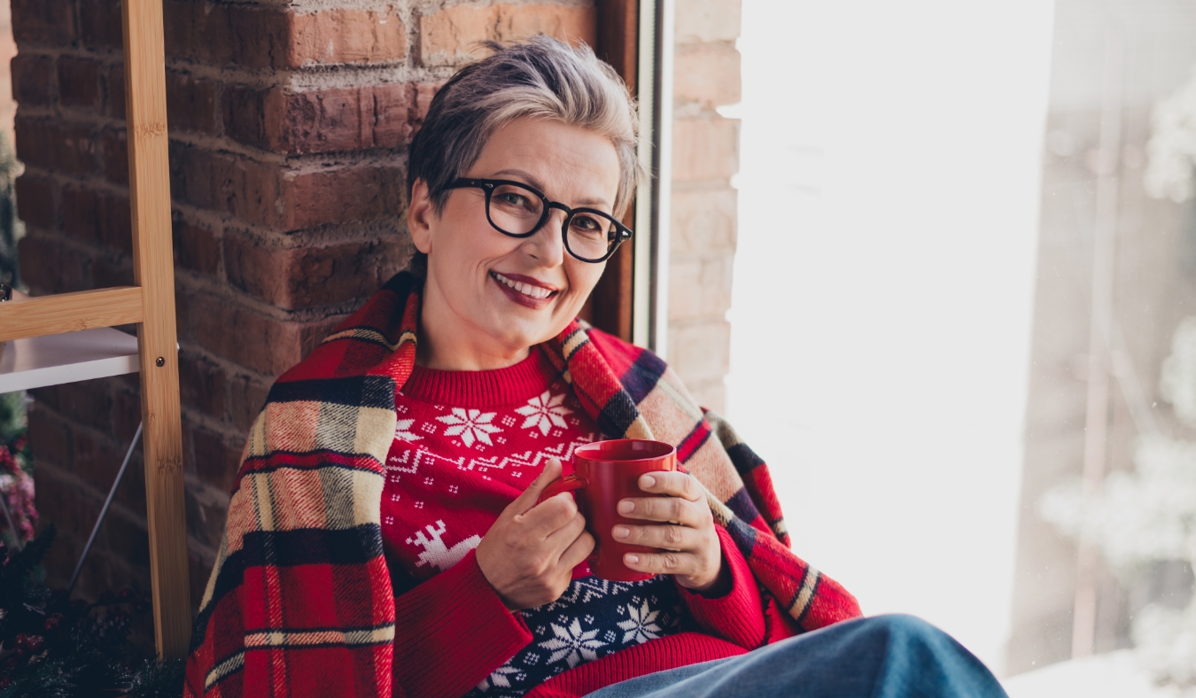 woman drinking warm tea sitting by window