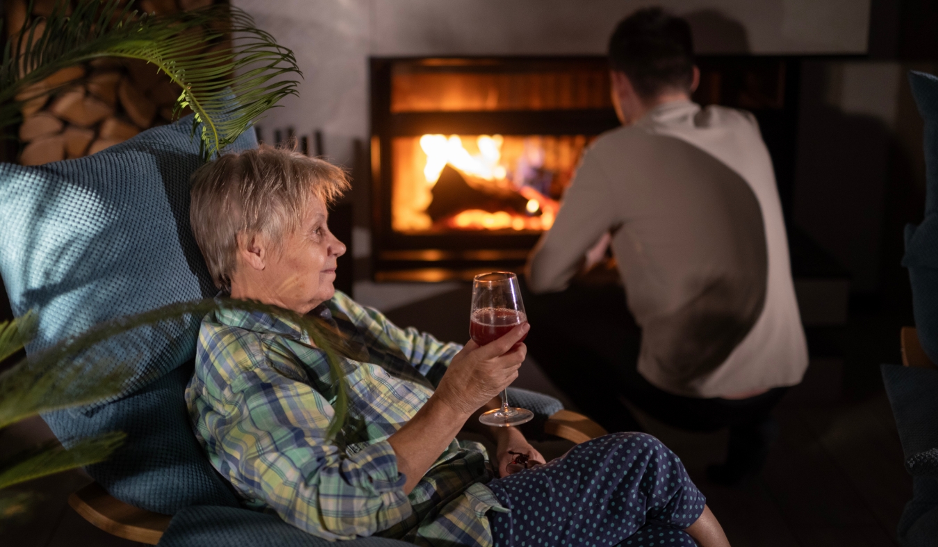 woman enjoying glass of wine by fireplace