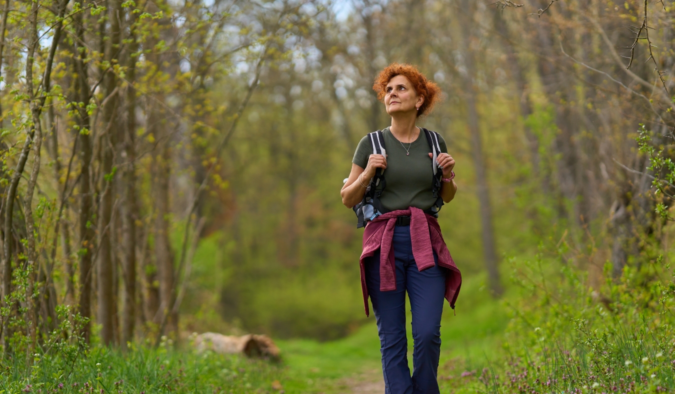 older woman hiking alone along a quiet forest trail