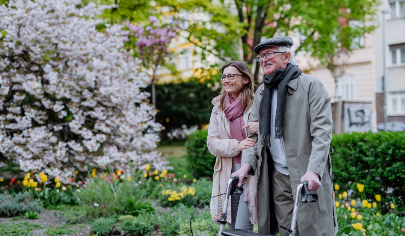 senior man walking with adult daughter in park during spring