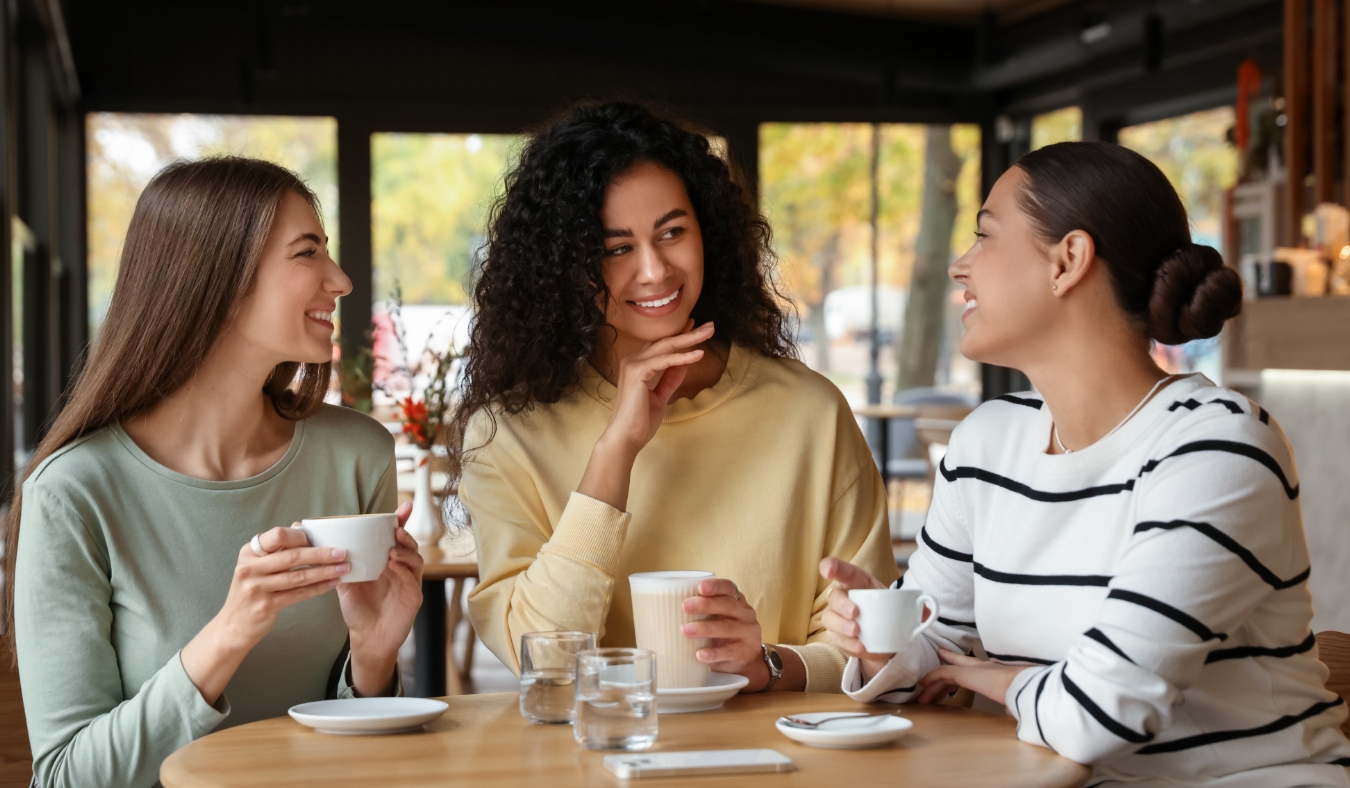 women with coffee drinks chatting in cafe