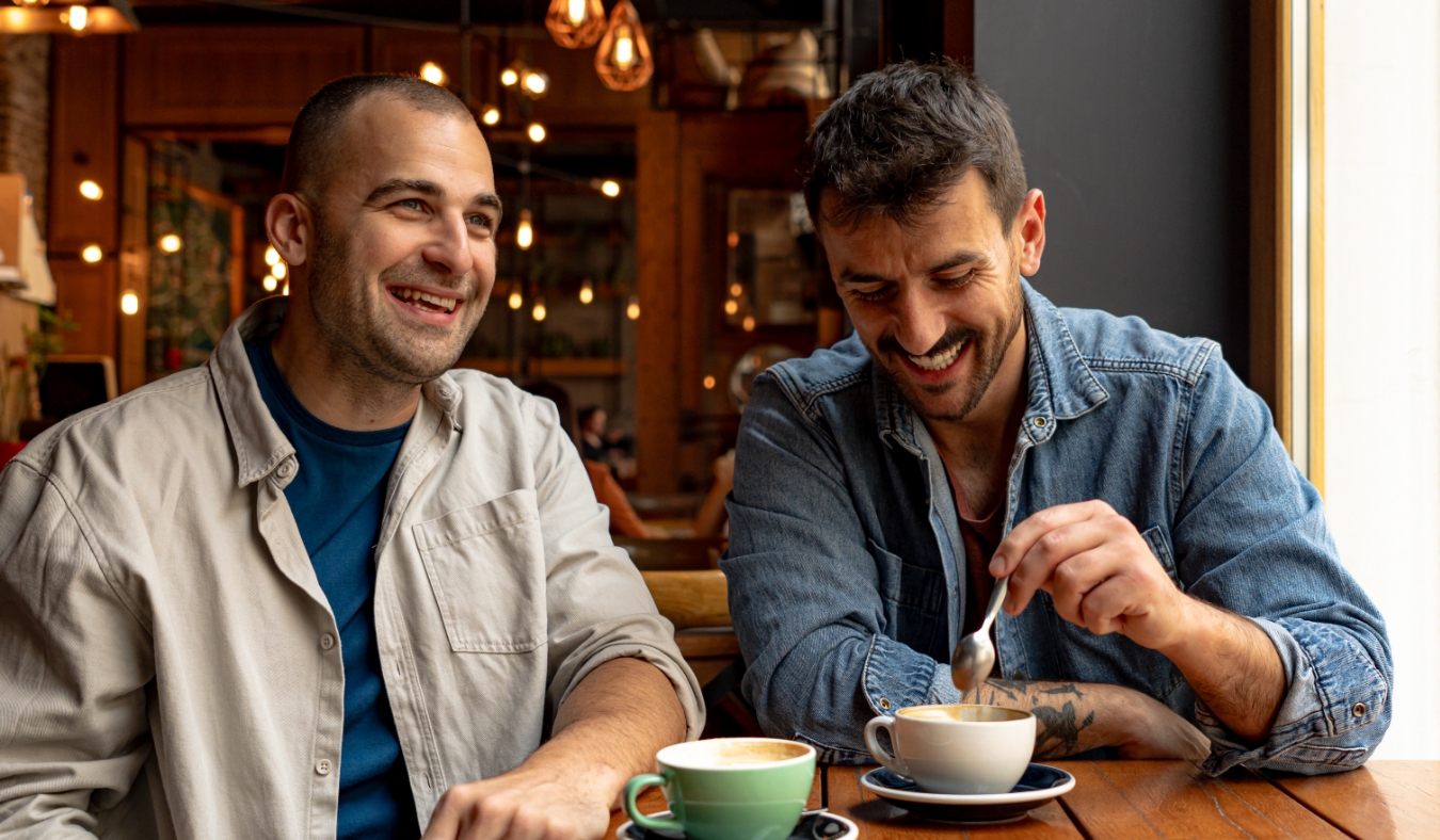 two male friends talking over coffee in cafe