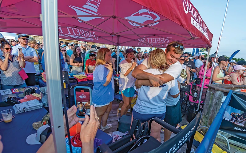 Jarrett Bay's Margaret and crew member from Builders Choice in celebration under the Jarrett Bay tent as a crowd cheers at Big Rock Landing