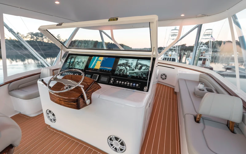 Flybridge helm of the Jarrett Bay 68 featuring integrated navigation screens, teak accents, and panoramic visibility