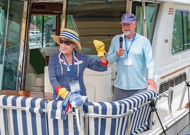 Smiling woman in striped outfit and hat christening her Sabre yacht with support from Bluewater staff