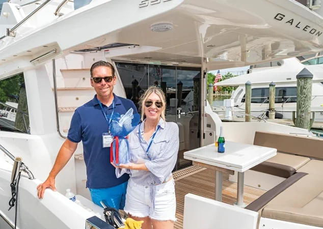 Couple smiling aboard a Galeon yacht with a gift basket during the Bluewater Summer Cruise in St. Michaels
