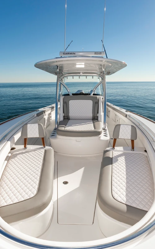 Forward seating area of the Valhalla V-33 featuring diamond-stitched cushions and a center console under clear skies