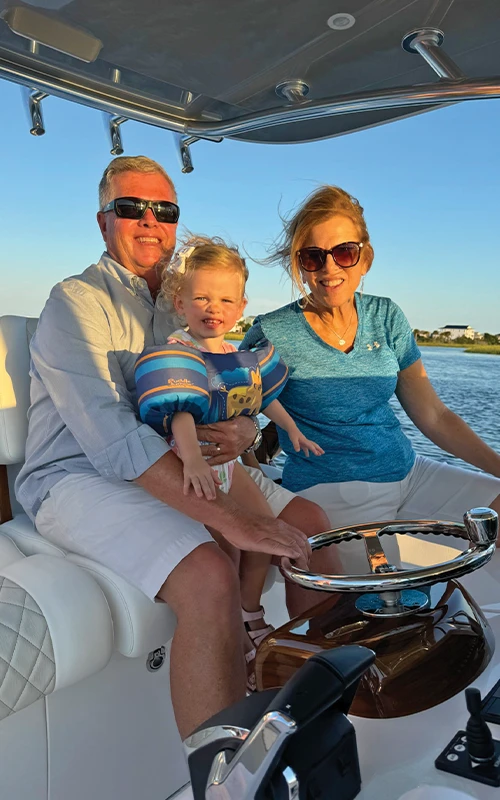 John Donoghue and family enjoying a sunny day cruise aboard their Valhalla V-33, seated at the helm with grandchild