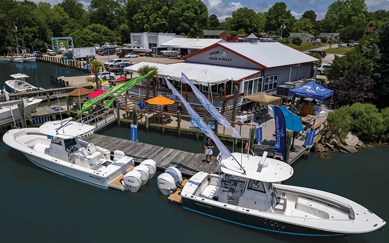 Two Regulator boats on display at a waterfront event hosted by Bluewater Yacht Sales, with branded flags and tents