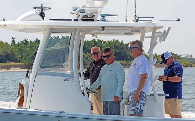 Group of boaters chatting at the helm of a Regulator 30XO during a demo day ride near shore.