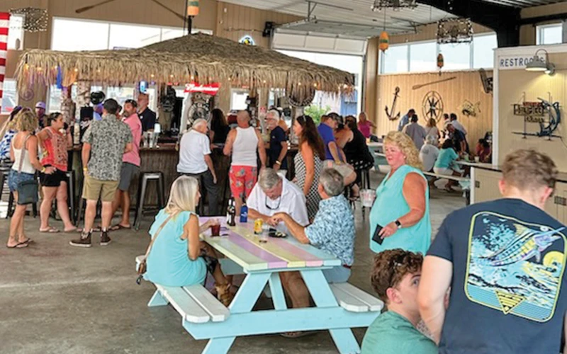 Crowd gathered at a tiki bar-themed event hosted by Bluewater Yacht Sales, celebrating Regulator ownership