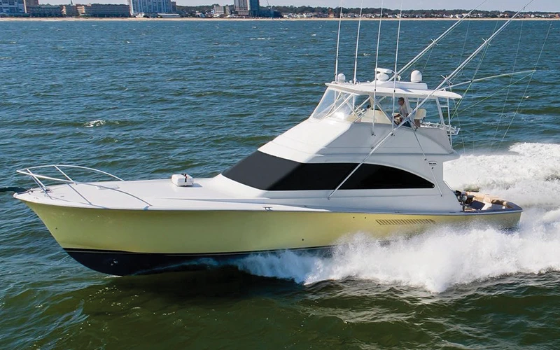 Side view of a 54' Ocean sportfishing yacht cruising offshore at high speed with a wake trailing behind