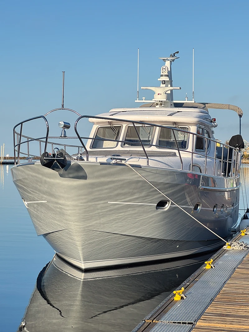 Elling E4 moored at a dock, reflecting in calm, glassy water under a clear sky