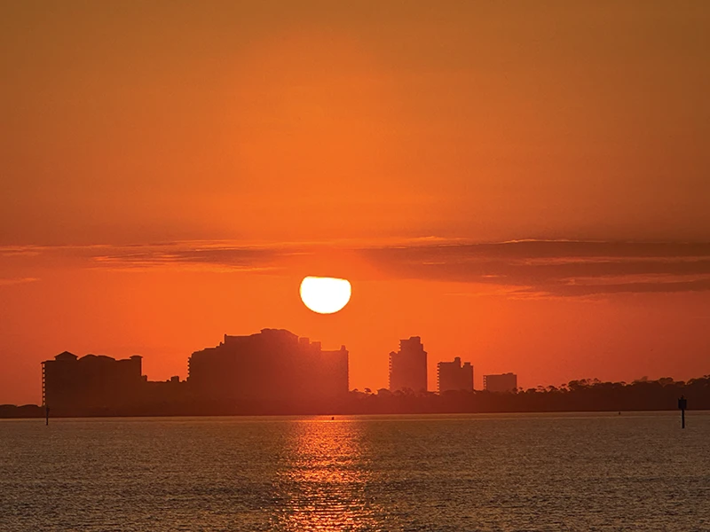Dramatic orange sunset over a city skyline viewed from the water during the Elling E4’s Gulf Coast leg of the journey