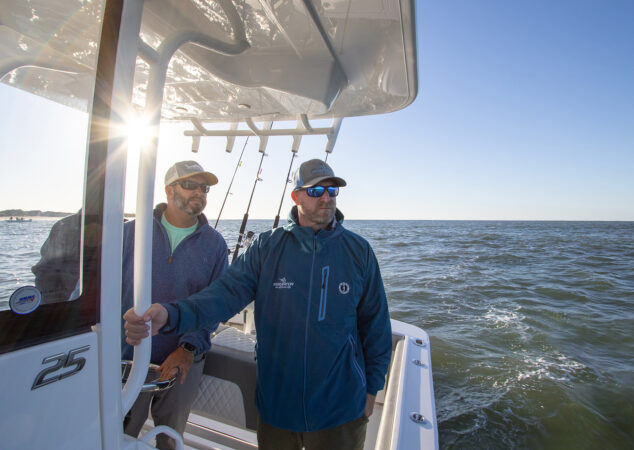Two men standing at the helm of a Regulator 25 while cruising offshore