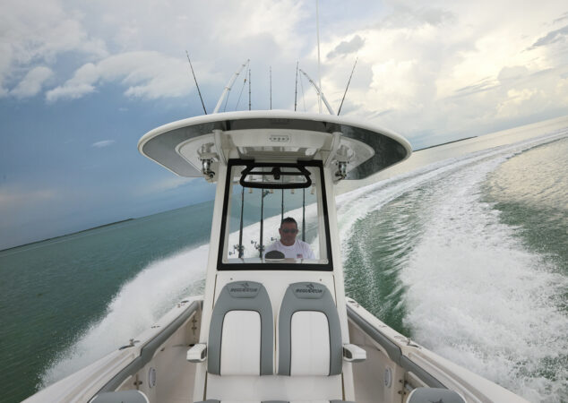 Helm view of the Regulator 23 with captain steering through a sharp turn, rods secured in holders