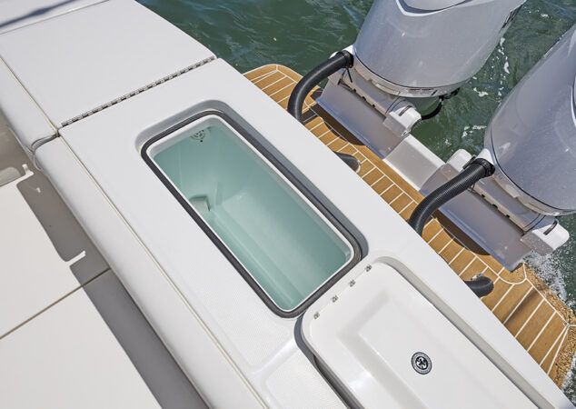 Open livewell with blue interior set into aft deck beside engines