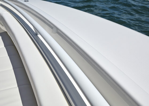 Forward seating area with cushioned lounge and stainless steel grab rail along the gunwale