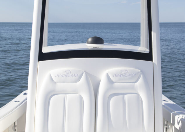Cushioned dual helm seats with armrests, storage, and T-top overhead