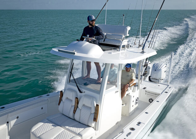 Close-up of the Regulator 30XO upper helm with captain driving barefoot, showcasing second station seating
