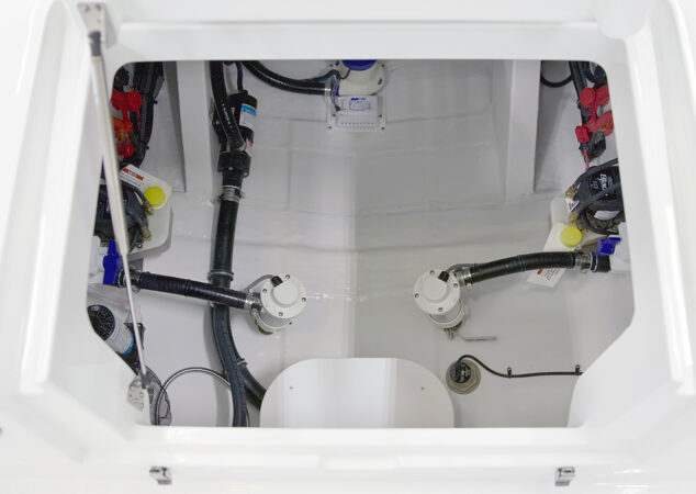 Bilge access hatch open, showing plumbing, pumps, and wiring neatly organized below deck