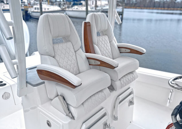 Pair of deluxe helm chairs with diamond stitching and teak arm accents at the console