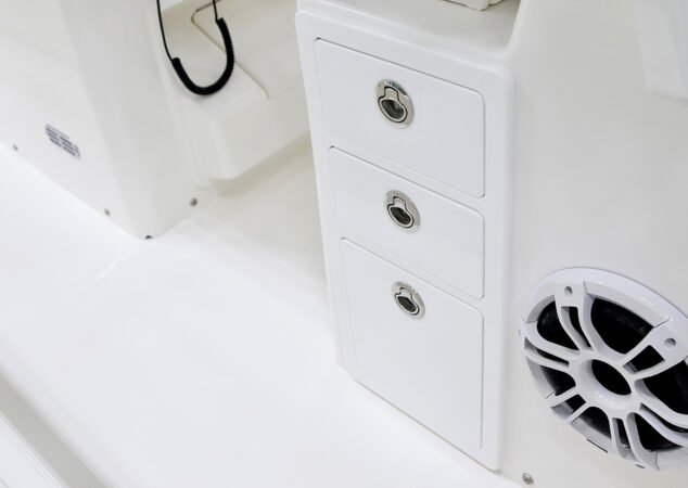 Cockpit storage drawers with stainless latches beside a Fusion marine speaker