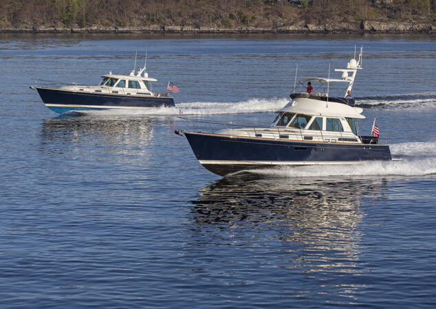 Two Sabre yachts running side by side on the water, with American flags flying at the sterns