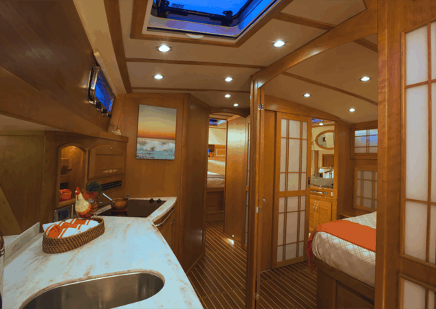Interior passageway showing galley, shoji-style sliding doors, and stateroom entrances with overhead skylight