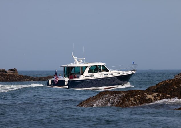Sabre 45 Salon Express cruising past rocky shoreline with passengers relaxing in the cockpit