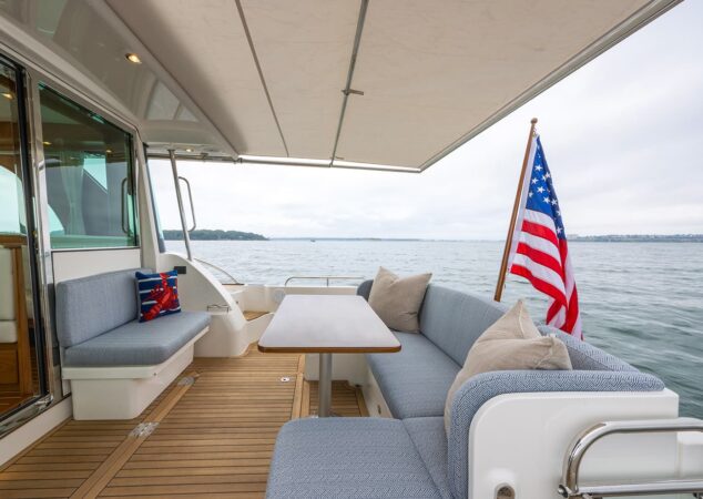 Cockpit seating of Sabre 45 Salon Express with teak table, upholstered settees, and American flag aft