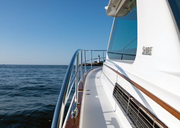 Forward starboard side deck and handrail of the Sabre 43 with a lighthouse in the distance